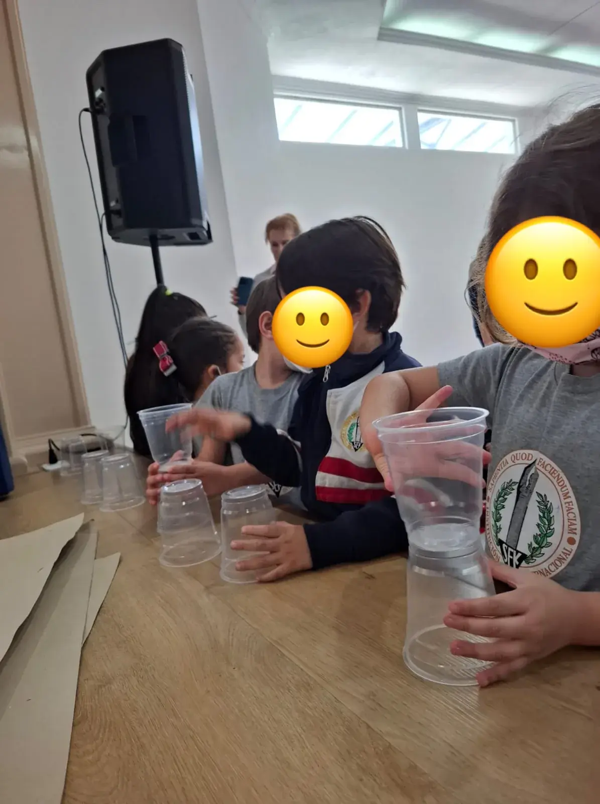 Manos infantiles moviendo vasos sobre una mesa para crear un efecto de sonido